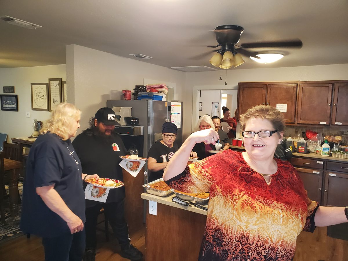 Guests and staff sharing a meal in the kitchen