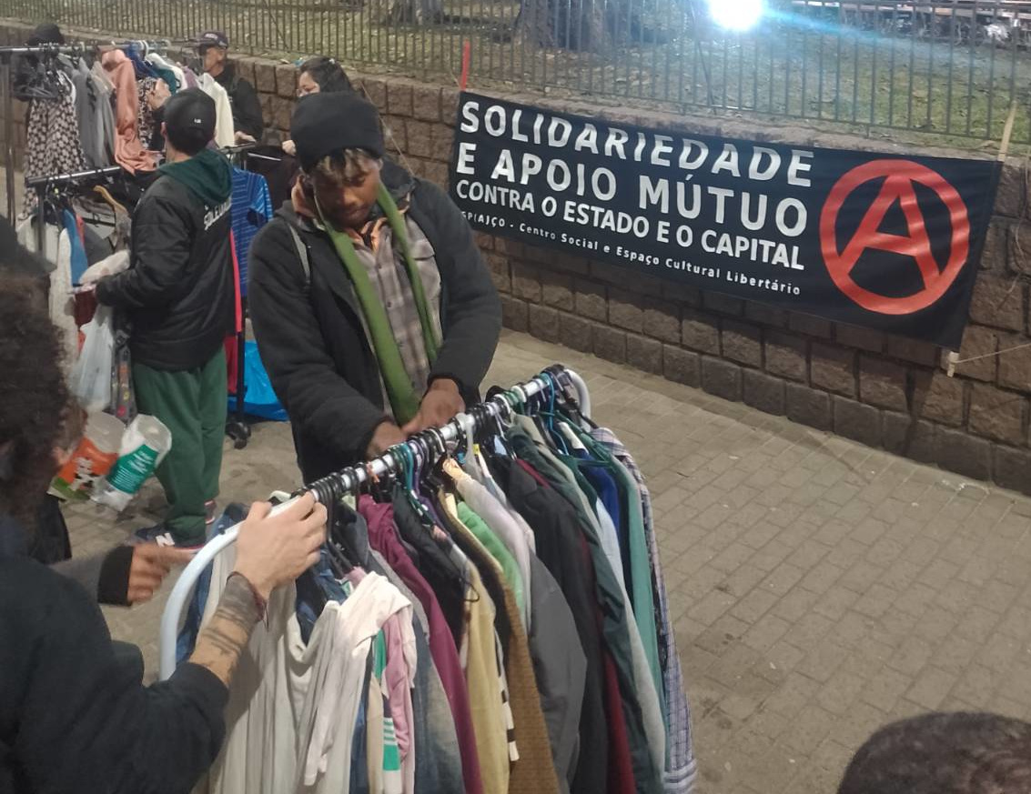 Photo of a person selecting clothes from a rack on the street.