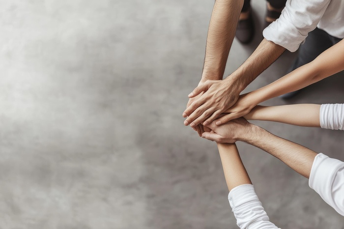 A group of people putting their hands togetherDescription automatically generated