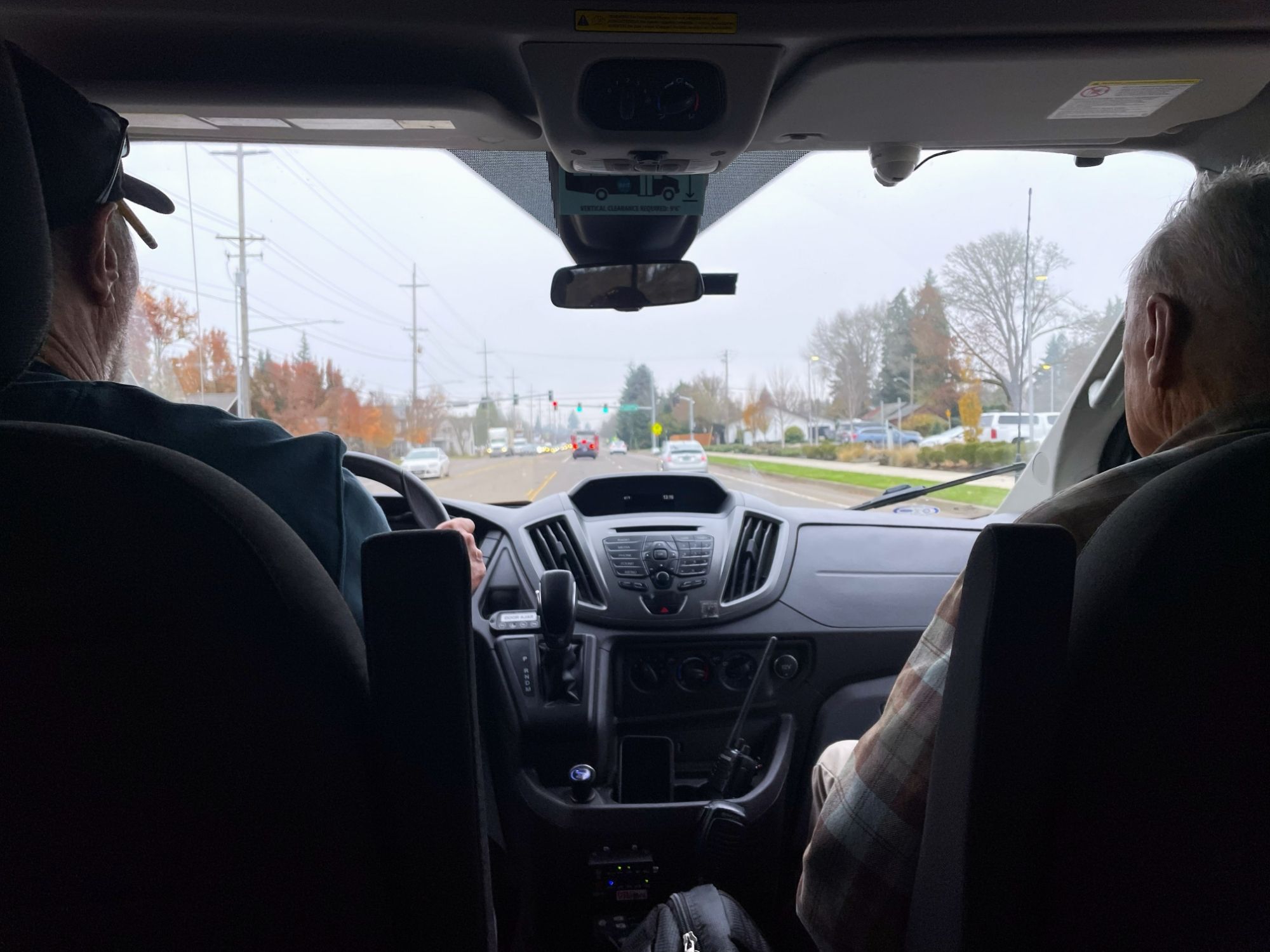 Dial A Bus driver with a client in a vehicle driving through town.