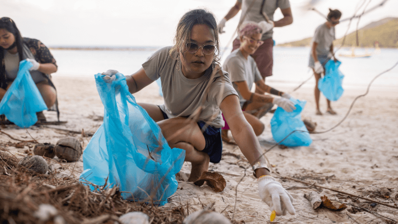 Image shows a changemaker cleaning up her local beach. 