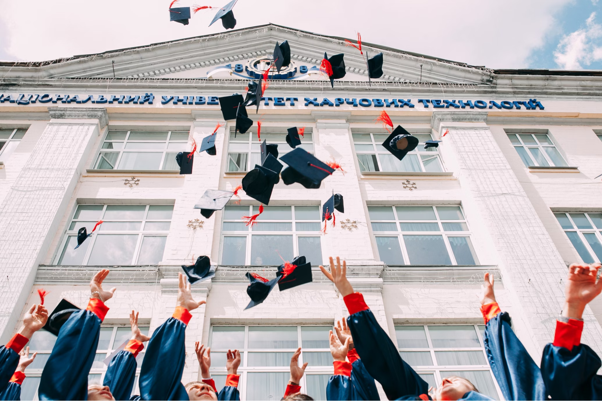 Image shows students throwing their graduation caps into the air. 